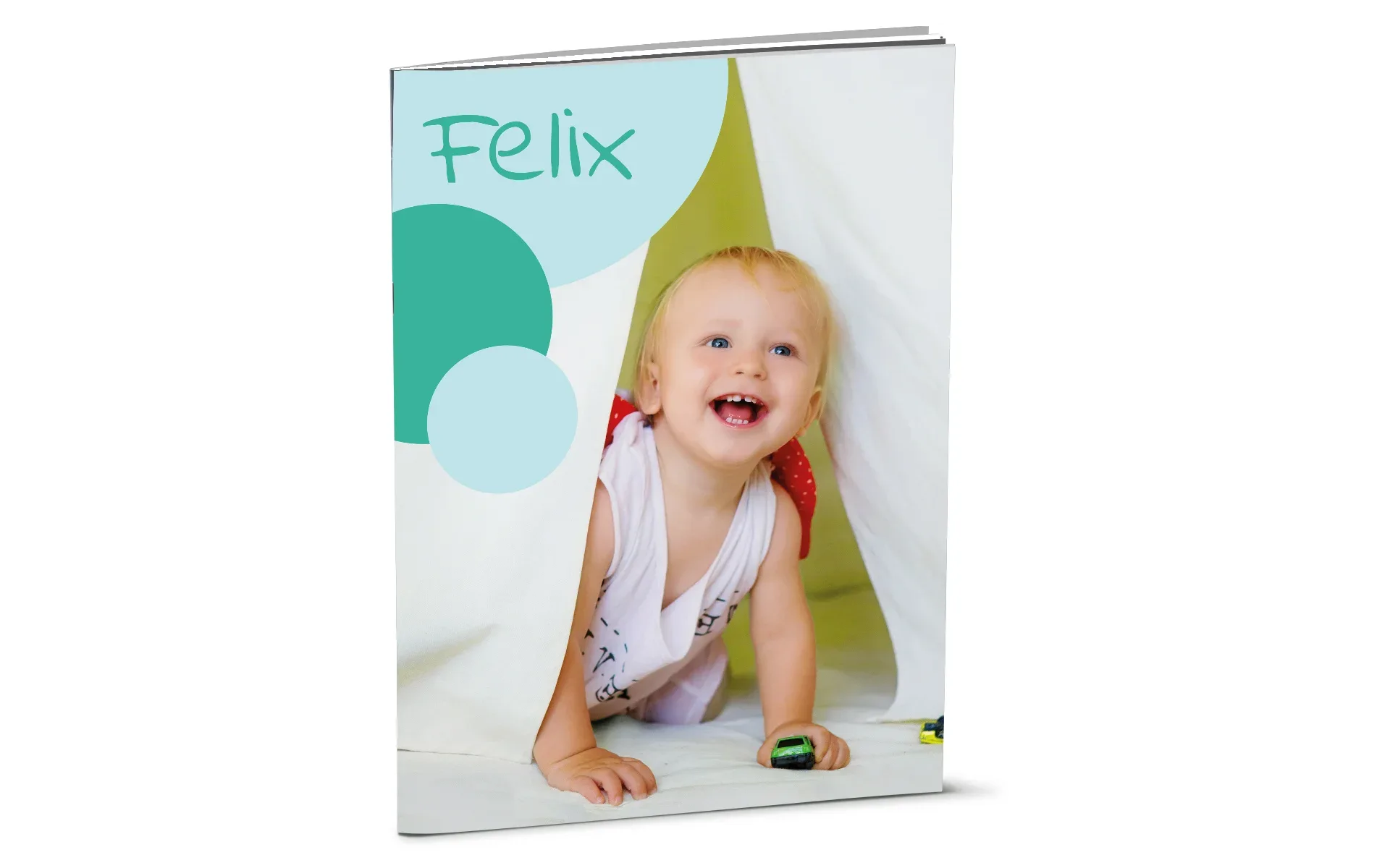 Ein aufgestelltes Happy Fotobuch ca. A4 hoch mit dem Titel Felix zeigt ein Baby.