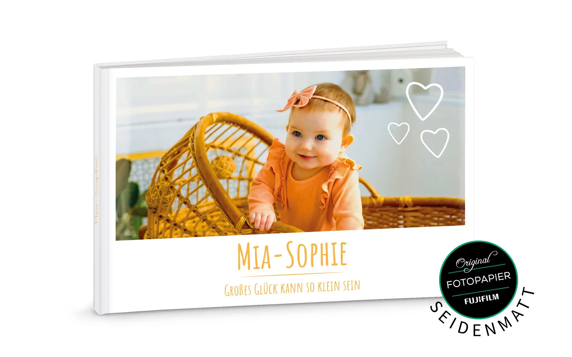 Ein aufgestelltes Happy Fotobuch ca. A4 quer mit dem Titel Mia-Sophie zeigt ein Baby und Herz Cliparts.