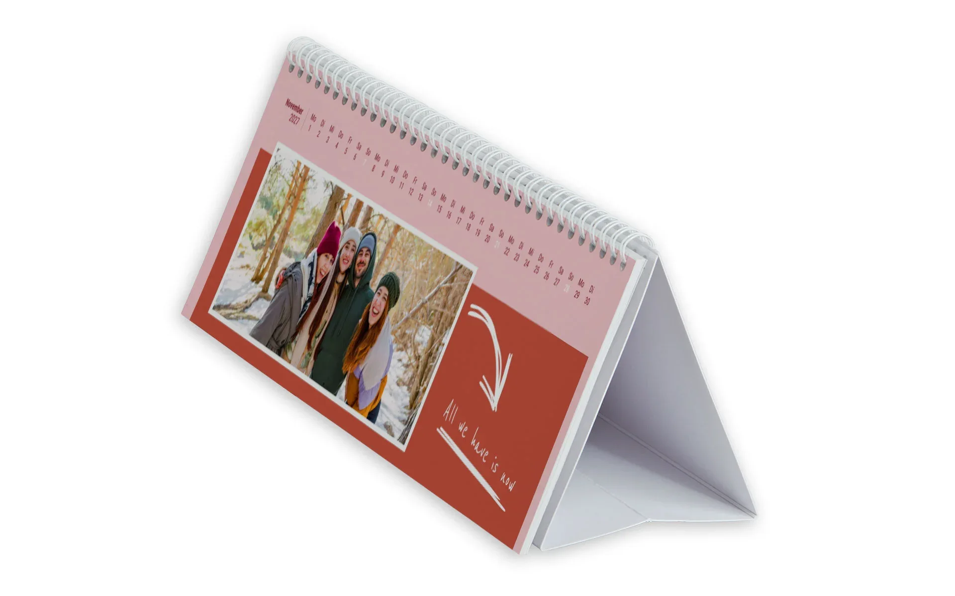 Ein Tischkalender in einer seitlichen Ansicht mit dem Text All we have is now zeigt 4 Freunde im Wald vor einem rosa Hintergrund und einem roten rechteckigen Clipart.