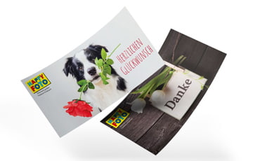 Zwei Geschenkgutscheine von HappyFoto: Eine mit einem Hund und eine mit der Aufschrift "Danke" und Blumen.