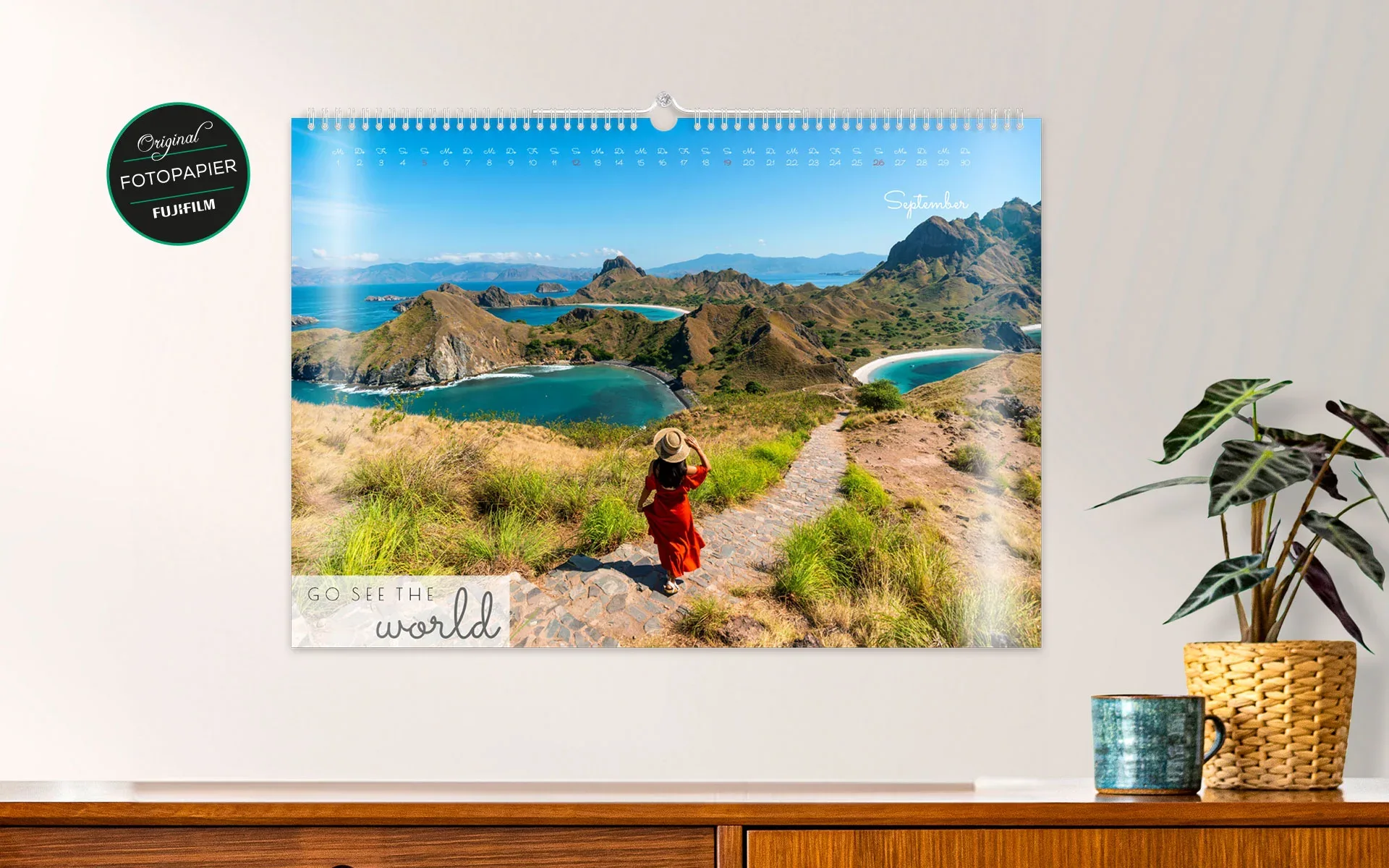 HappyFotokalender ca. A3 quer – aufgehängt Ein aufgehängter HappyFotokalender ca. A3 quer mit dem Text Go see the world zeigt ein vollflächiges Foto einer Frau in der Natur.