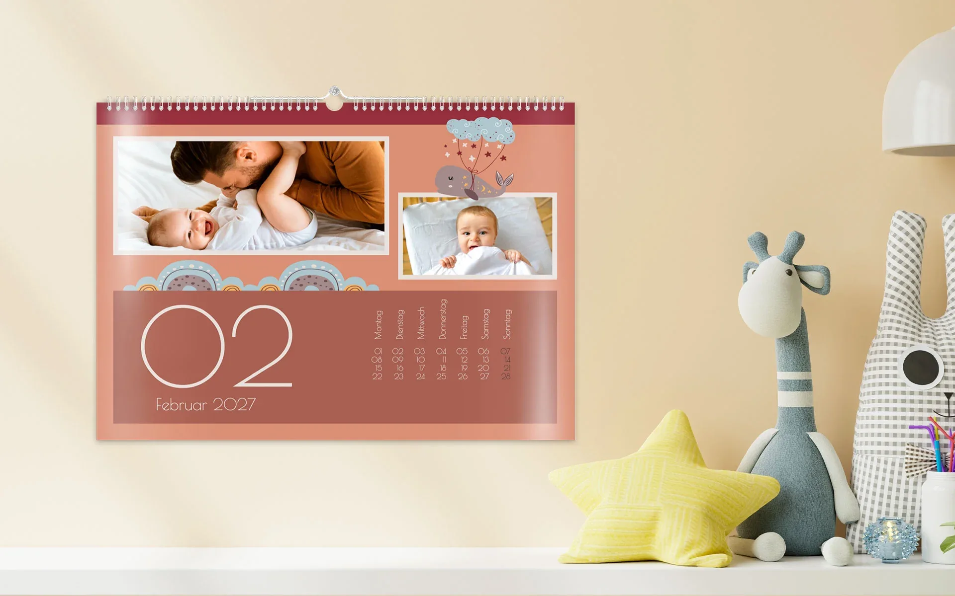 HappyFotokalender ca. A4 quer – aufgehängt Ein aufgehängter HappyFotokalender ca. A4 quer zeigt 2 Fotos von einem Baby und bunte Cliparts.