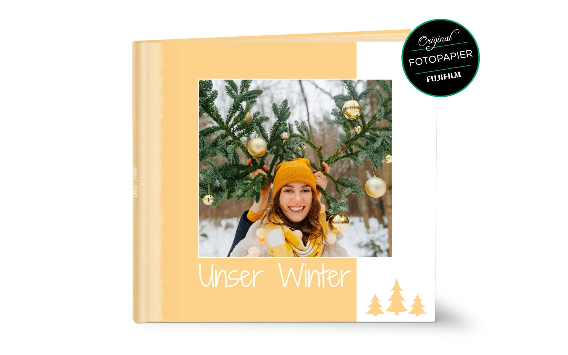 Ein aufgestelltes Happy Fotobuch ca. 30 x 30 cm mit dem Titel Unser Winter zeigt ein eine Frau mit zwei Tannenzweige.