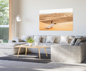 Eine Person in einem weißen Kleid geht über eine goldene Sanddüne.